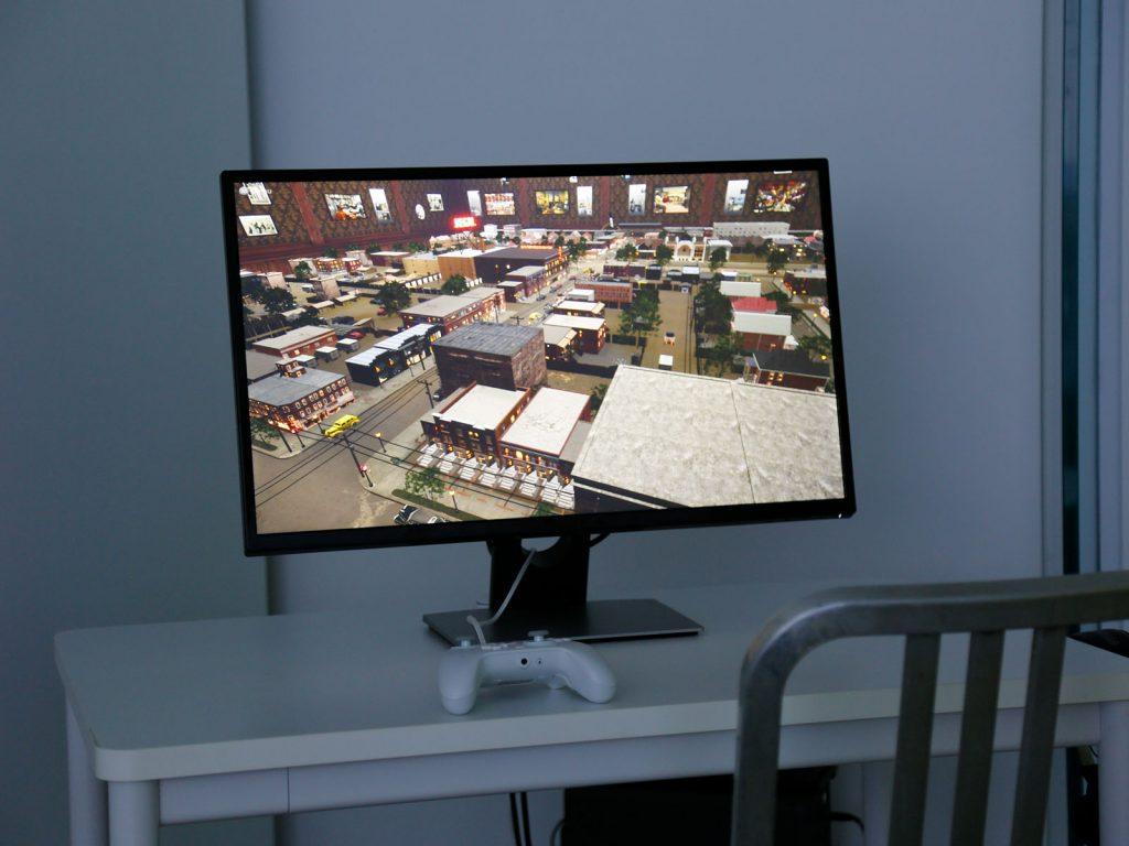 A computer monitor on a desk with a game controller.