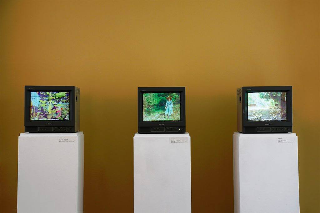 Three TV monitors with videos playing.