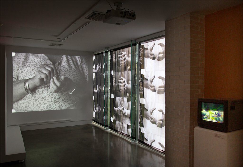 A projected video in the gallery. A window is covered with shades printed with film stills.