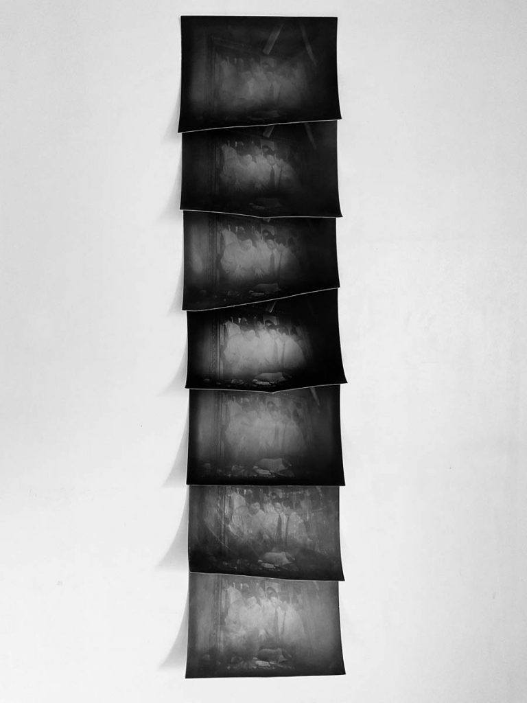 Seven black and white photographs installed vertically.
