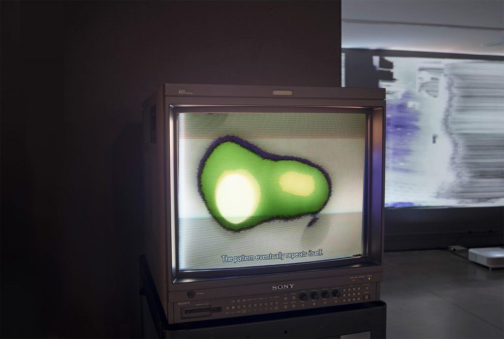 A CRT monitor displaying an abstract image with text that reads "The pattern eventually repeats itself."