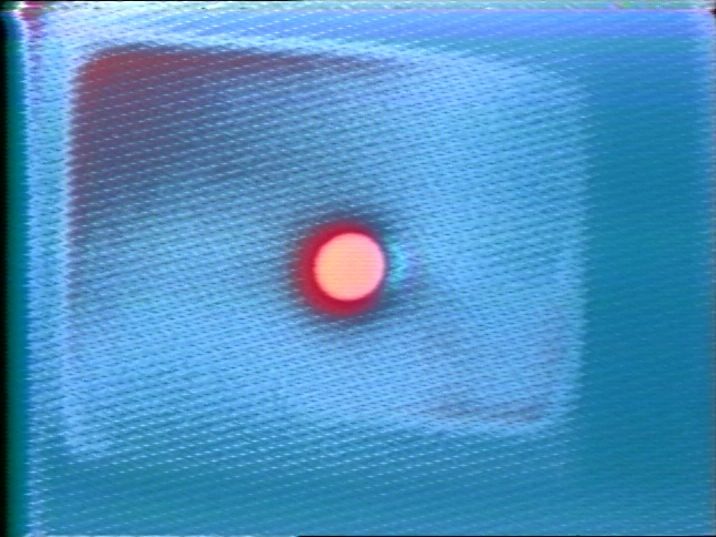 Video still of an abstract blue background with red dot in the middle.