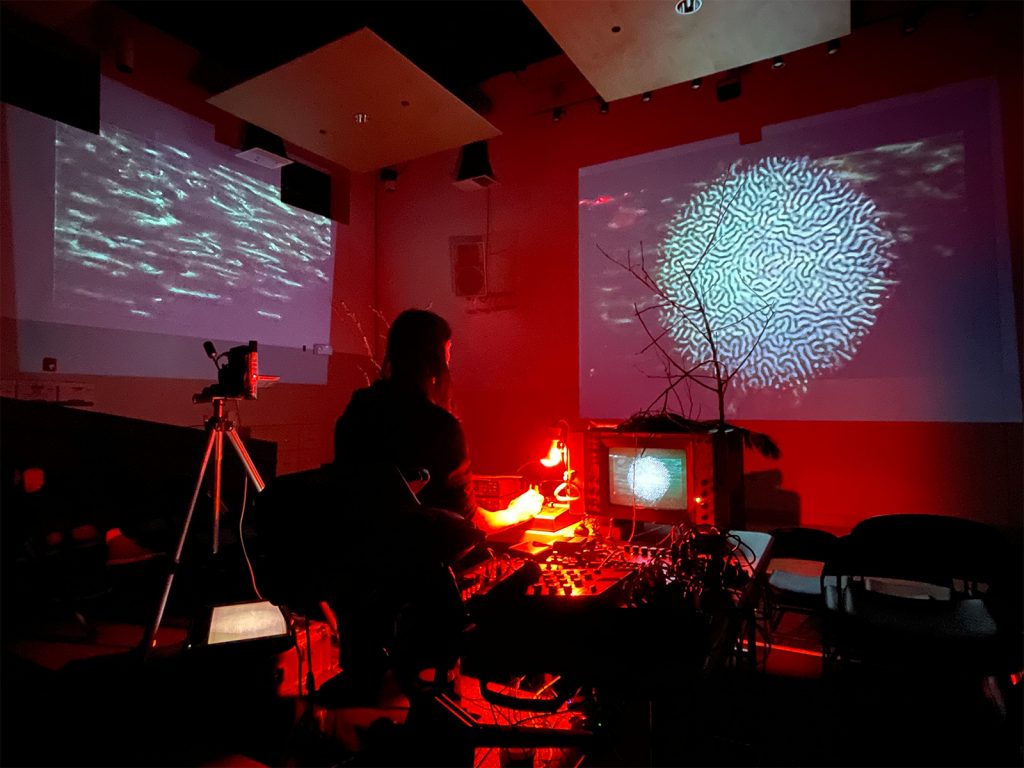 Joel Dow stands in the VSW theater between two projections.