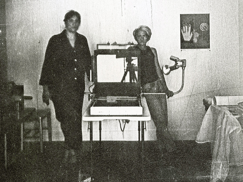 Black and white self portrait of the artists standing in the studio.