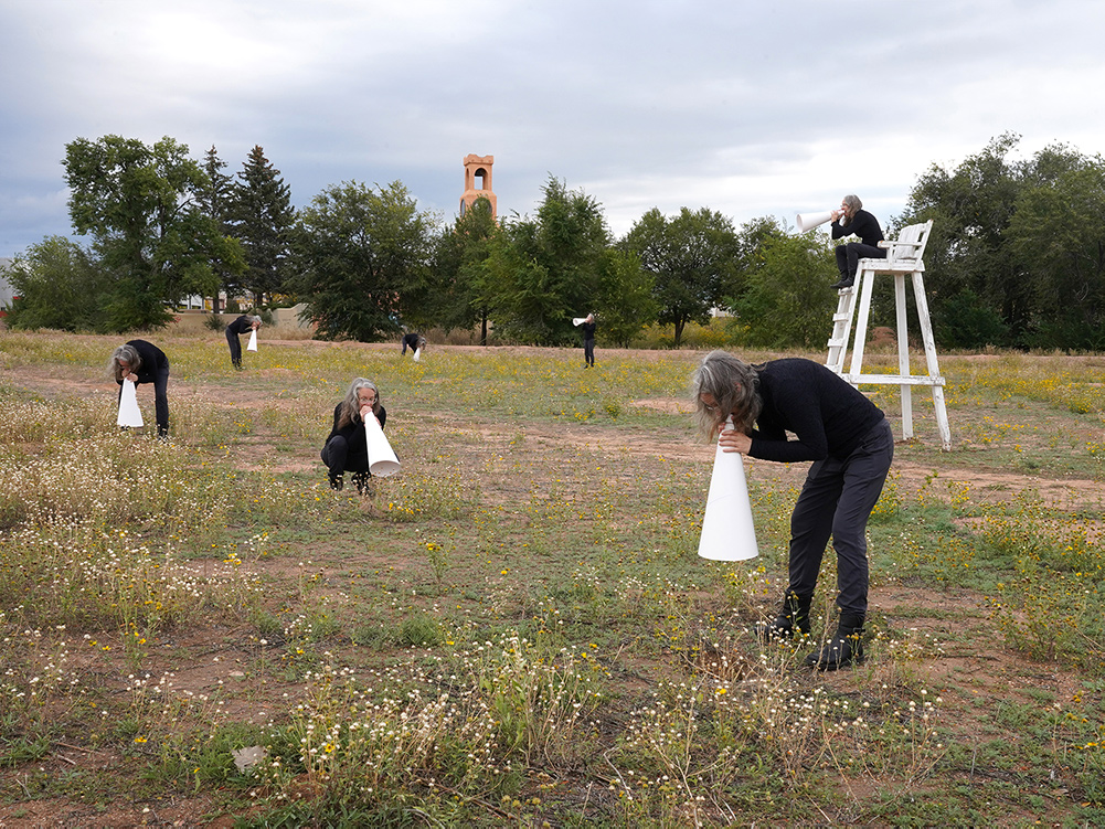 Photo of Margaret LeJeune standing in a field with a megaphone.