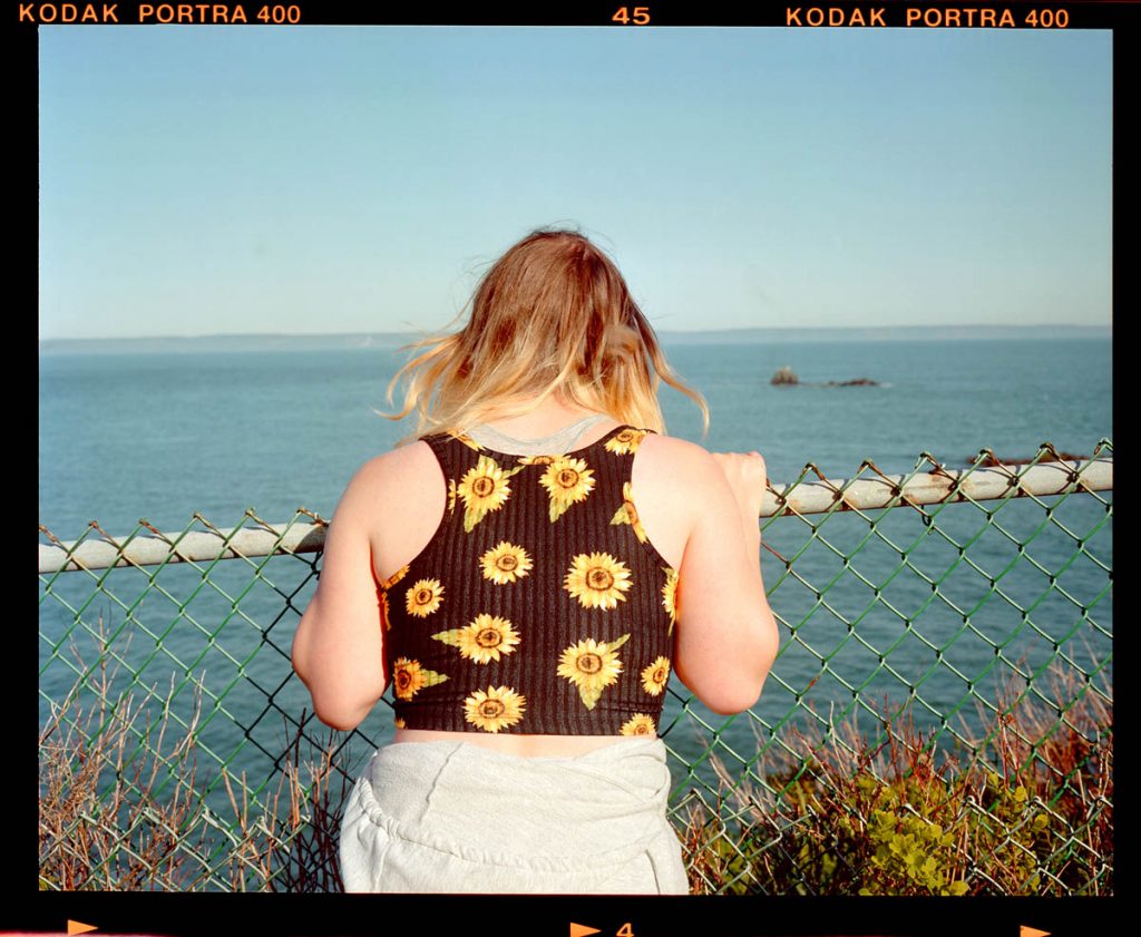 A woman peers over a railing into the water.