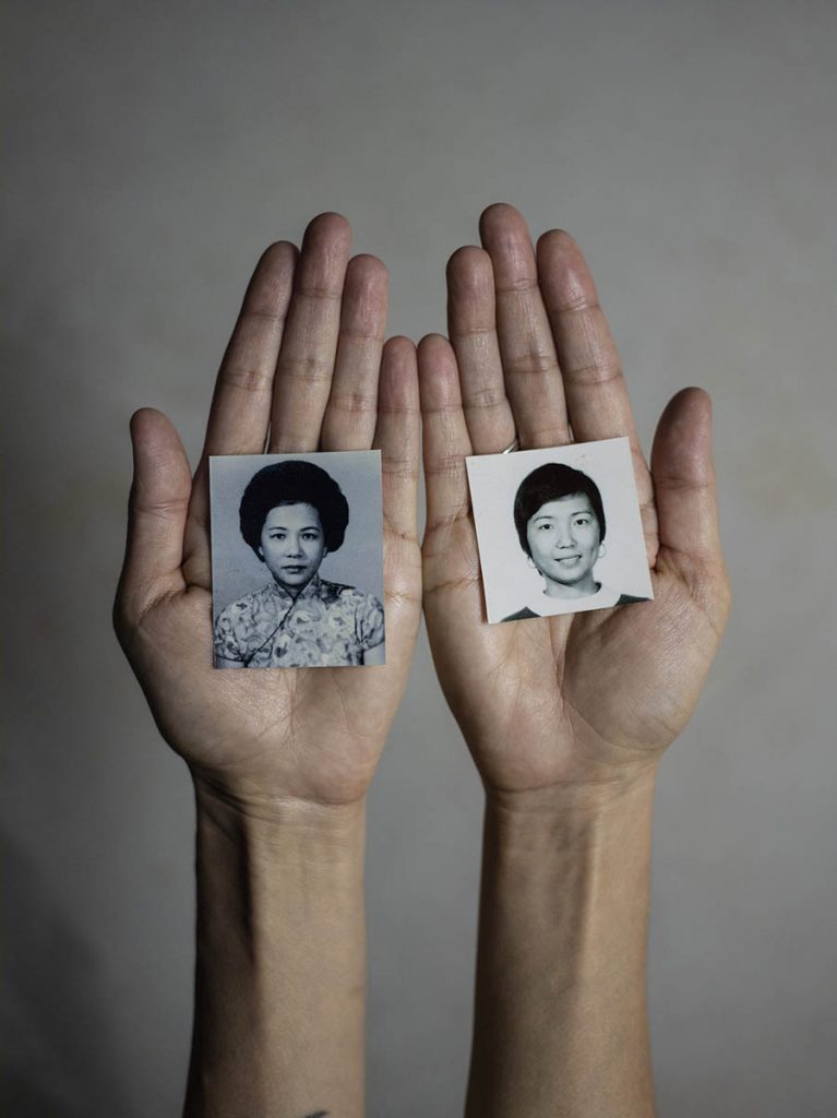 Two hands hold two photo portraits.